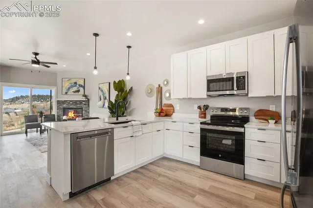 a kitchen with stainless steel appliances granite countertop a stove top oven a sink dishwasher and a refrigerator with wooden floor