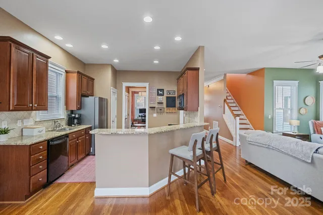 a kitchen with stainless steel appliances granite countertop a refrigerator a sink dishwasher a stove and white countertops with wooden floor