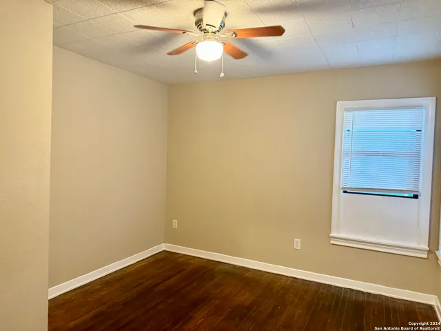 an empty room with a ceiling fan and wooden floor