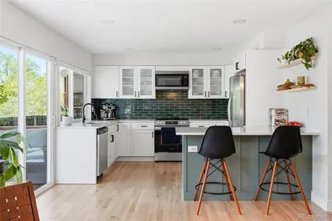 a kitchen with stainless steel appliances granite countertop a stove a sink a refrigerator white cabinets and wooden floor