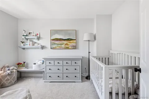 a bedroom with furniture a baby crib and a wooden floor
