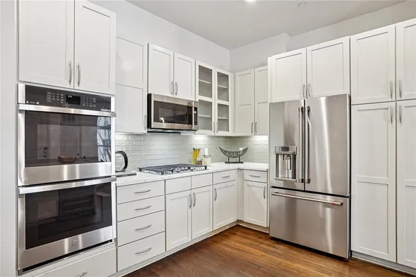 a kitchen with cabinets stainless steel appliances and wooden floor