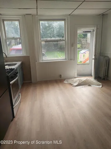 a view of an empty room with a window and wooden floor