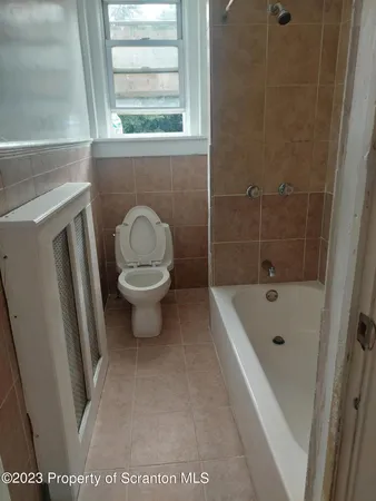 a bathroom with a sink a toilet a window and a shower