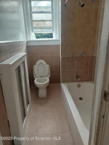 a bathroom with a sink a toilet a window and a shower