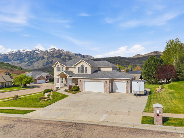 6849 North Black Powder Road Mountain Green, UT 84050 - Photo 36 of 43 Multi-story residence featuring a brick and siding exterior with a multi-car garage, pitched shingle roof, and established landscaping