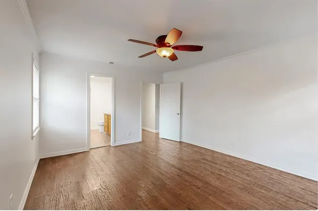 an empty room with wooden floor ceiling fan and window