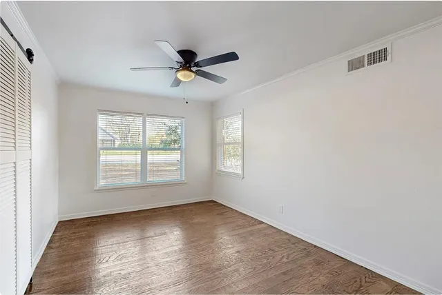 a view of empty room with wooden floor and fan