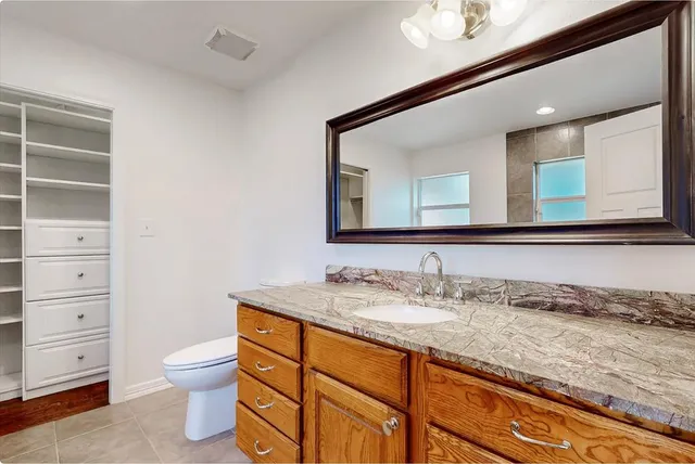 a bathroom with a granite countertop toilet sink and a mirror