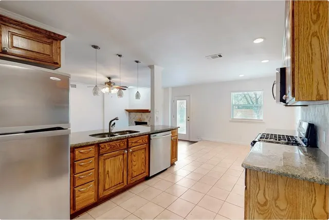 a kitchen with stainless steel appliances granite countertop a refrigerator a stove and a sink with wooden floor