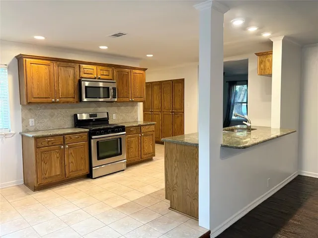 a kitchen with stainless steel appliances granite countertop a stove a sink and a microwave