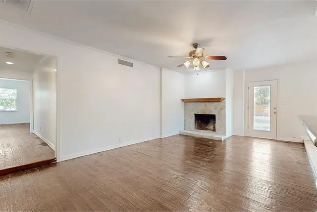 an empty room with chandelier fan and fireplace