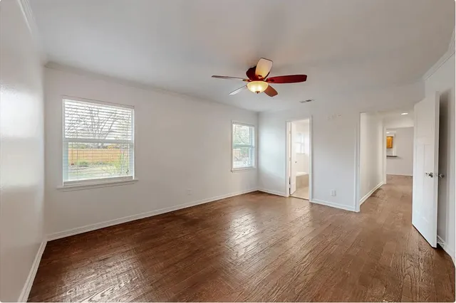 a view of an empty room with a window and wooden floor