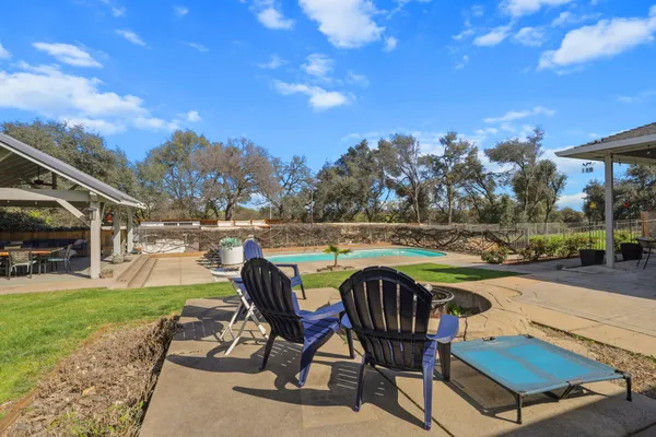 a view of a swimming pool with a patio and a yard