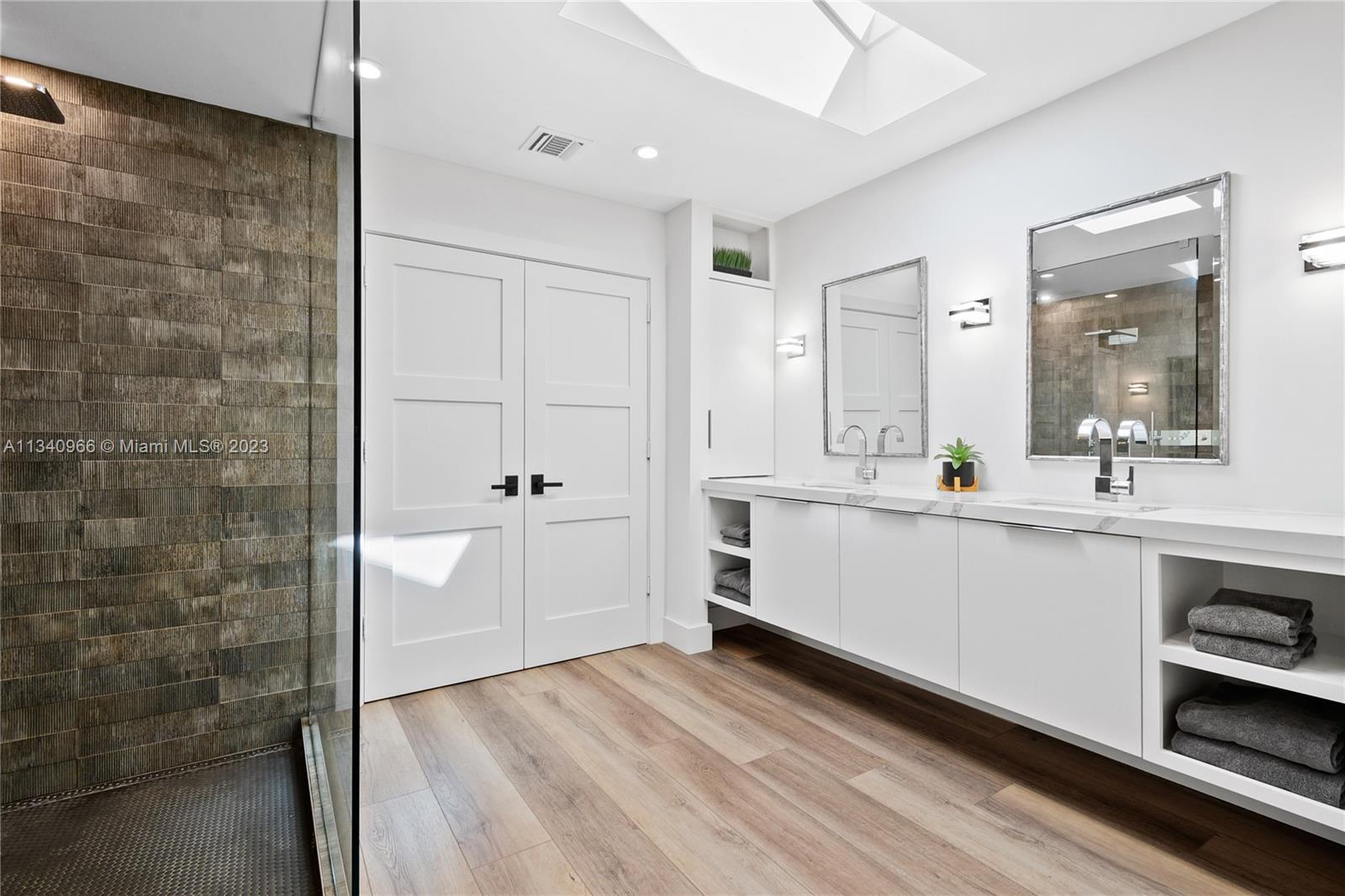 136 Sand Pine Drive Jupiter, FL 33477 - Photo 12 of 30 a bathroom with a double vanity sink a toilet a mirror and shower