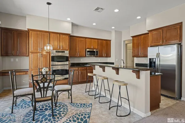 a kitchen with stainless steel appliances kitchen island granite countertop a refrigerator a stove a sink with a dining table and chairs