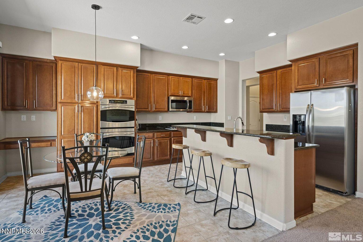 735 Sienna Park Drive Reno, NV 89512 - Photo 9 of 24 a kitchen with stainless steel appliances kitchen island granite countertop a refrigerator a stove a sink with a dining table and chairs