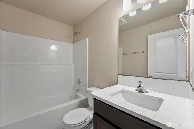 a bathroom with a bathtub shower sink vanity mirror and toilet