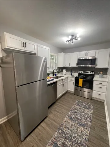 a kitchen with a refrigerator a stove top oven and cabinets