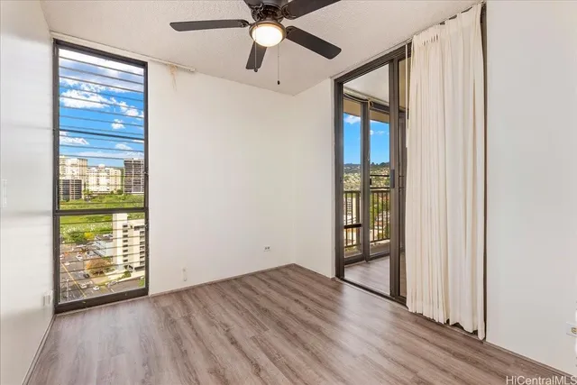 an empty room with wooden floor fan and windows