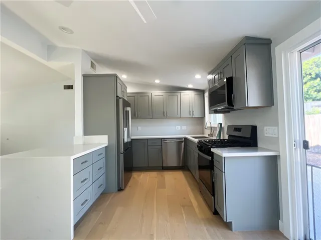 a large kitchen with stainless steel appliances granite countertop a stove a sink and a refrigerator