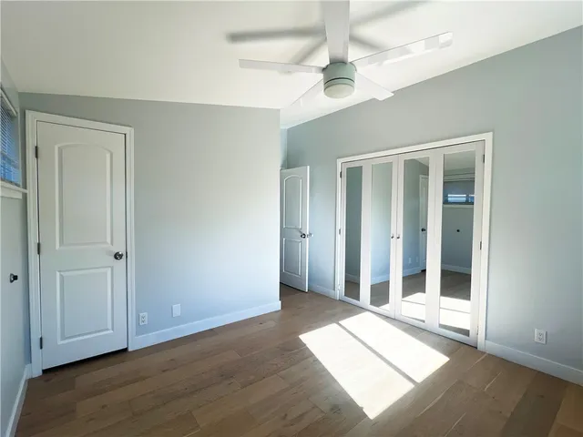 an empty room with wooden floor fan and windows