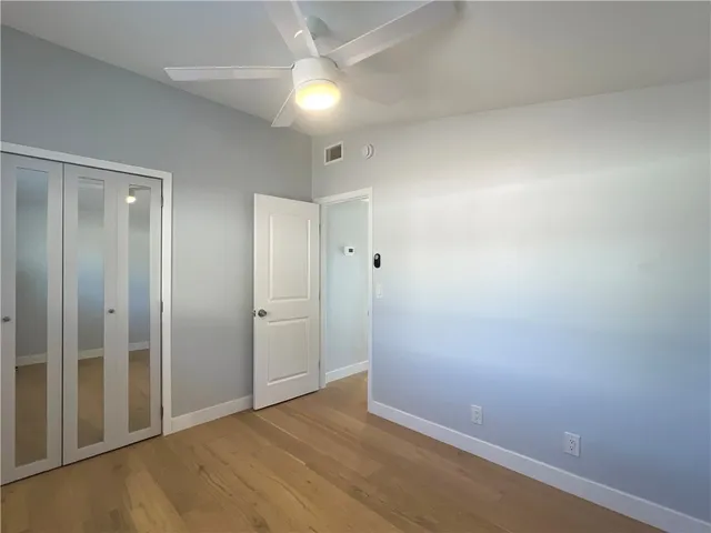an empty room with closet and a ceiling fan