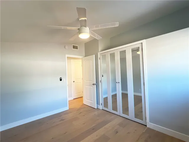 an empty room with wooden floor fan and windows