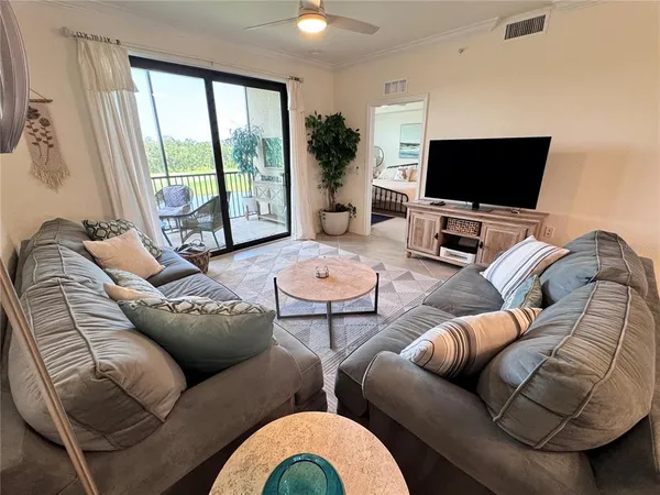 a living room with furniture a flat screen tv and a large window
