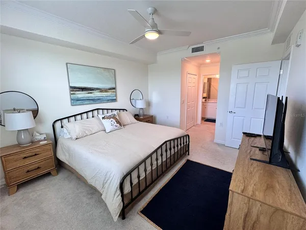 a bedroom with a bed a dresser and painting on the wall