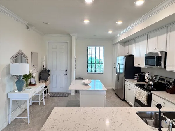 a large kitchen with stainless steel appliances granite countertop a sink dishwasher a stove a refrigerator a microwave oven a dining table and chairs with wooden floor