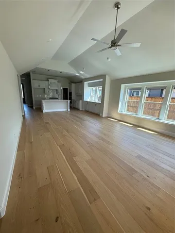 a view of empty room with wooden floor and fan