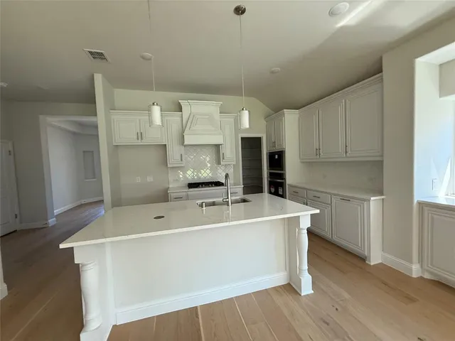 a living room with stainless steel appliances kitchen island granite countertop a sink and wooden floors