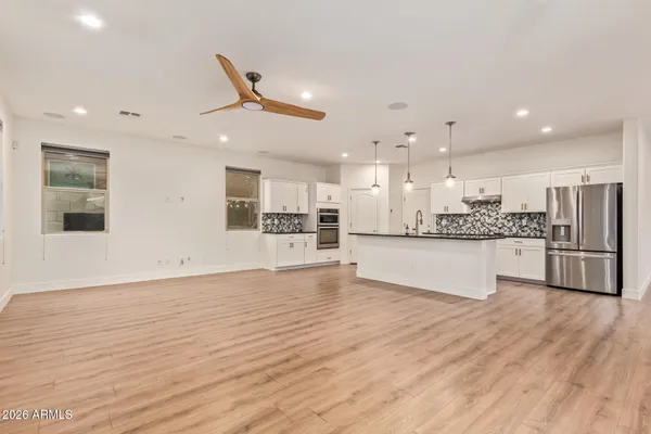 a large kitchen with stainless steel appliances kitchen island a large counter top and wooden floors