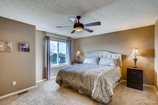 11181 Rodeo Circle Parker, CO 80138 - Photo 13 of 26 a bedroom with a bed and a chandelier