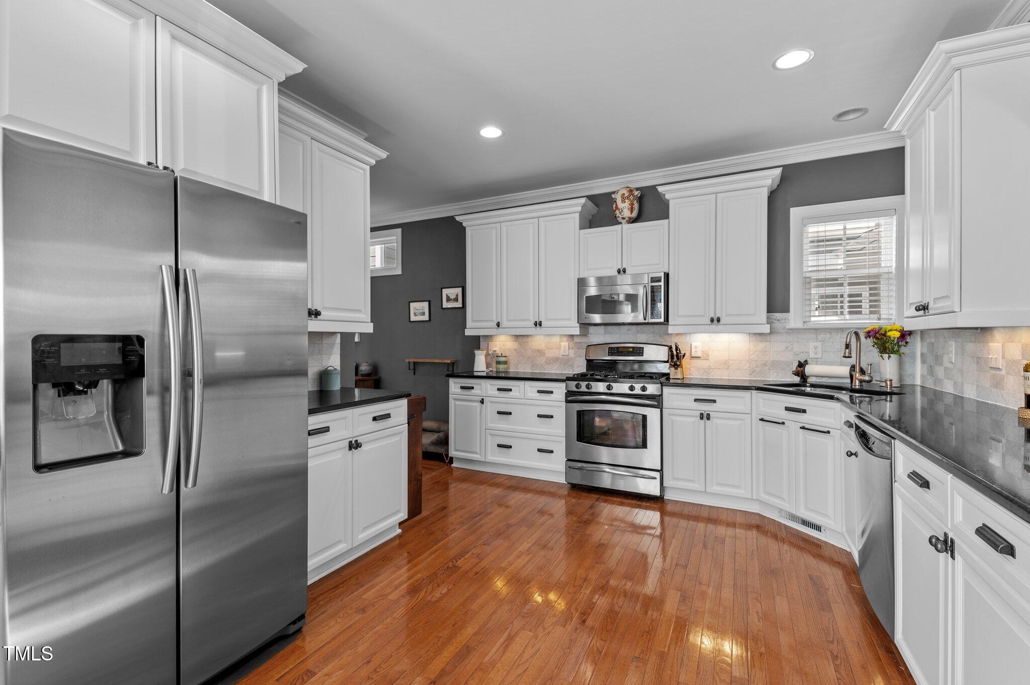 1209 Harp Street Raleigh, NC 27604 - Photo 16 of 39 a kitchen with stainless steel appliances granite countertop a refrigerator a stove and a sink with wooden floor