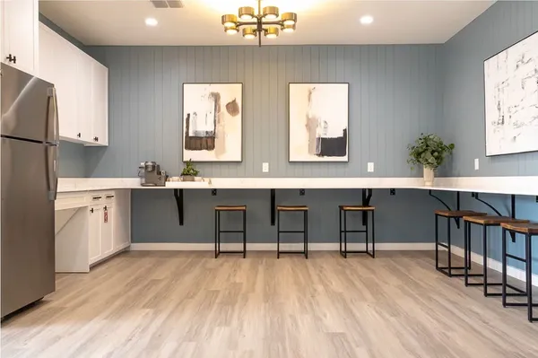 a room with stainless steel appliances kitchen island granite countertop a table chairs in it and wooden floors