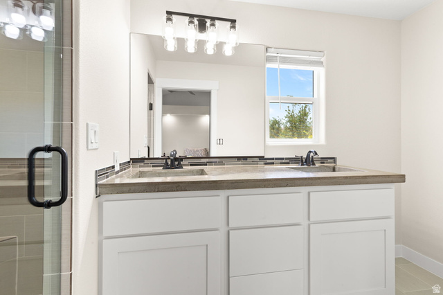2591 East Washington Dam Road Washington, UT 84780 - Photo 33 of 67 Dual-sink vanity featuring a light-toned countertop, mosaic tile backsplash, and matte black fixtures