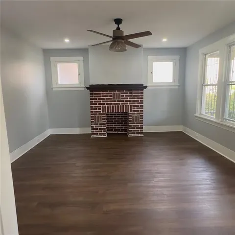 an empty room with wooden floor chandelier fan and windows