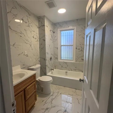 a bathroom with a bathtub shower sink mirror and toilet