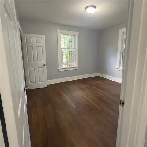 an empty room with wooden floor and windows with curtains