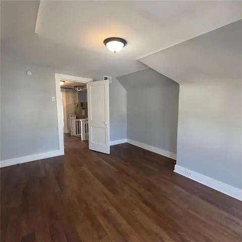 a view of an empty room with wooden floor and closet