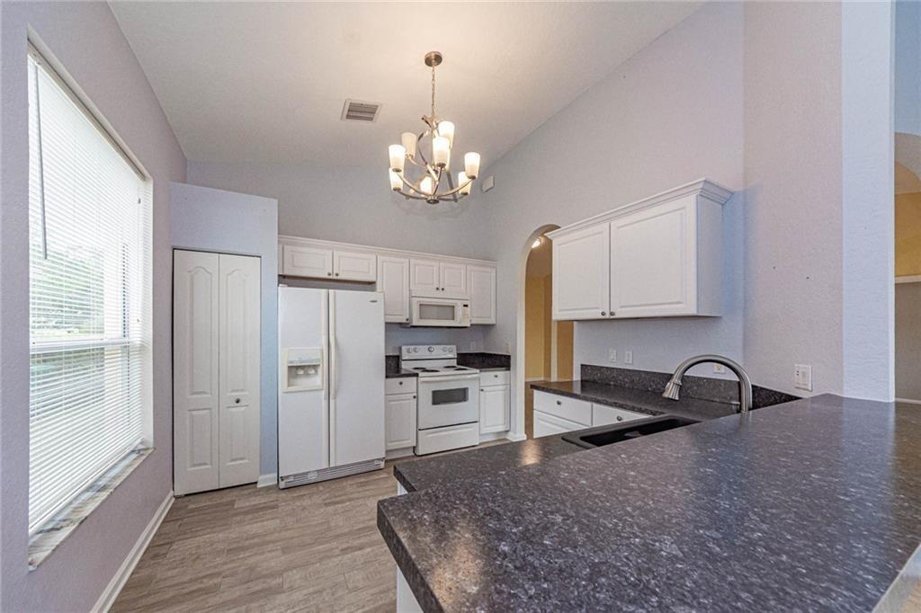 5544 Spanish River Road Fort Pierce, FL 34951 - Photo 8 of 35 a kitchen with stainless steel appliances granite countertop a refrigerator a stove a sink and a refrigerator with wooden floor