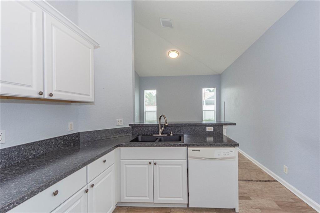5544 Spanish River Road Fort Pierce, FL 34951 - Photo 10 of 35 a kitchen with granite countertop white cabinets sink and window