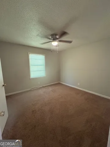 an empty room with windows and fan