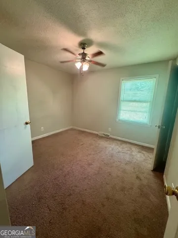 en empty room with windows and fan