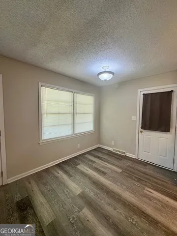 a view of an empty room with a window and wooden floor