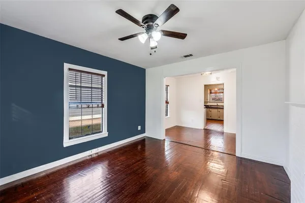a view of an empty room with window and wooden floor