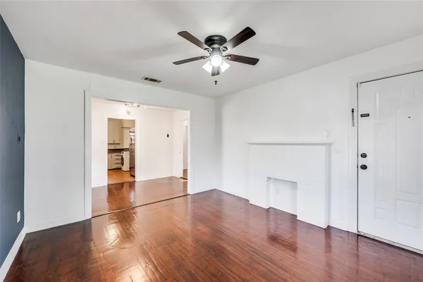 an empty room with wooden floor and a ceiling fan
