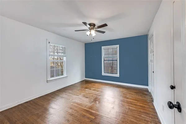 a view of an empty room with a window and wooden floor
